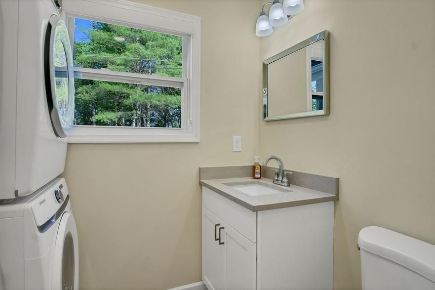 A bathroom with a sink , toilet , washer and dryer.