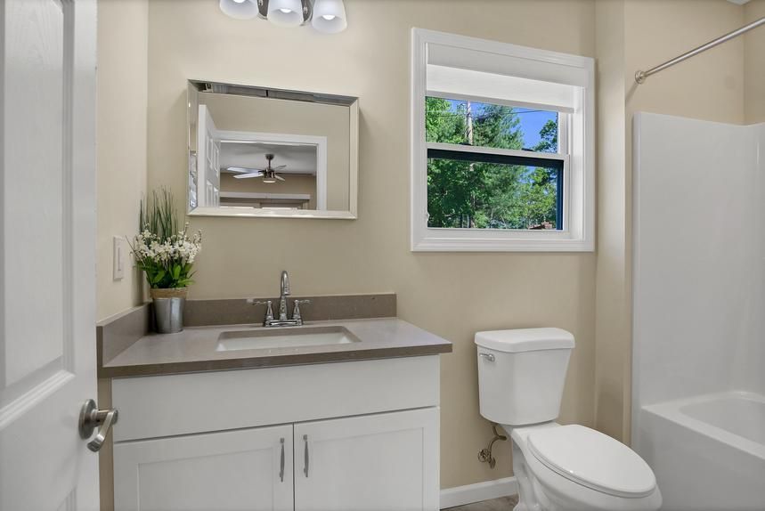 A bathroom with a sink , toilet , and window.