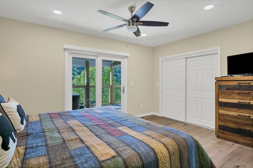 A bedroom with a king size bed and a ceiling fan.