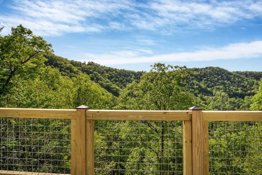 A wooden deck with a view of a forest and mountains.