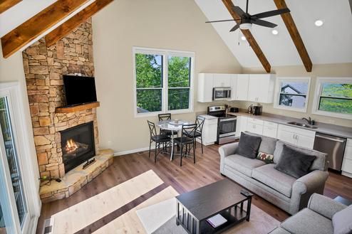 A living room with a couch , fireplace , table and chairs.