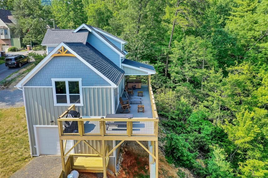 An aerial view of a house with a large deck surrounded by trees.