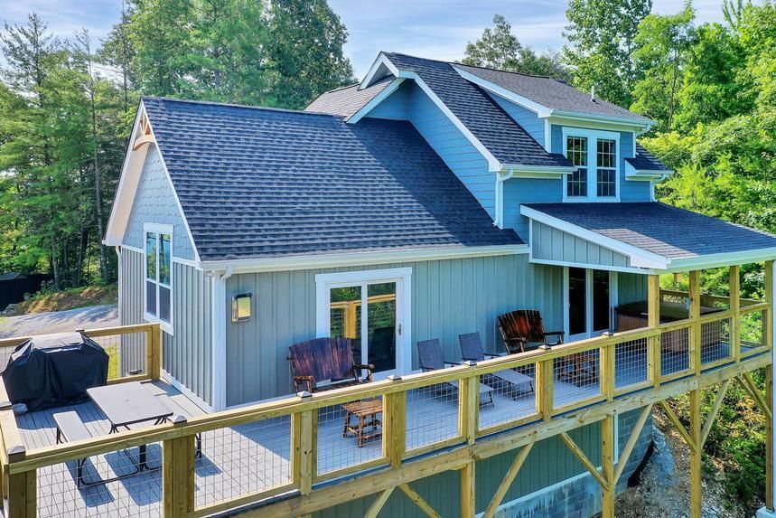An aerial view of a house with a large deck surrounded by trees.