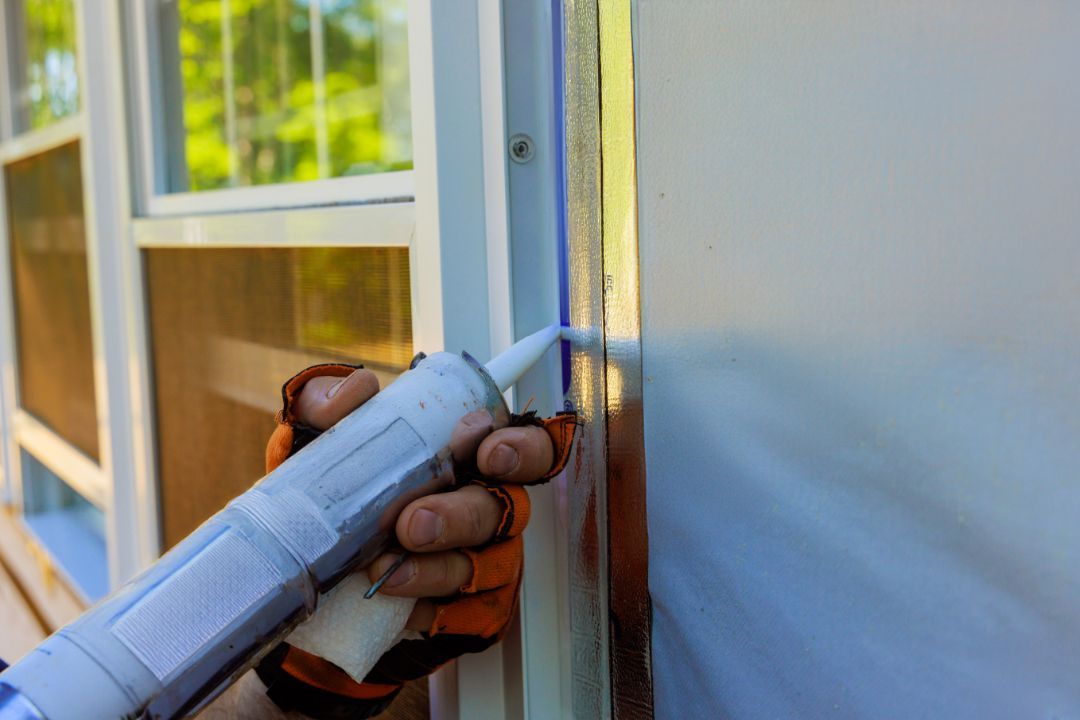 A person is applying caulk to a window frame.