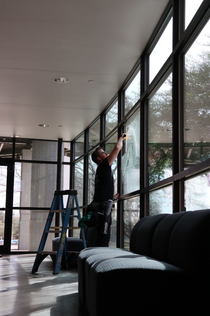 A man is standing on a ladder cleaning a window.