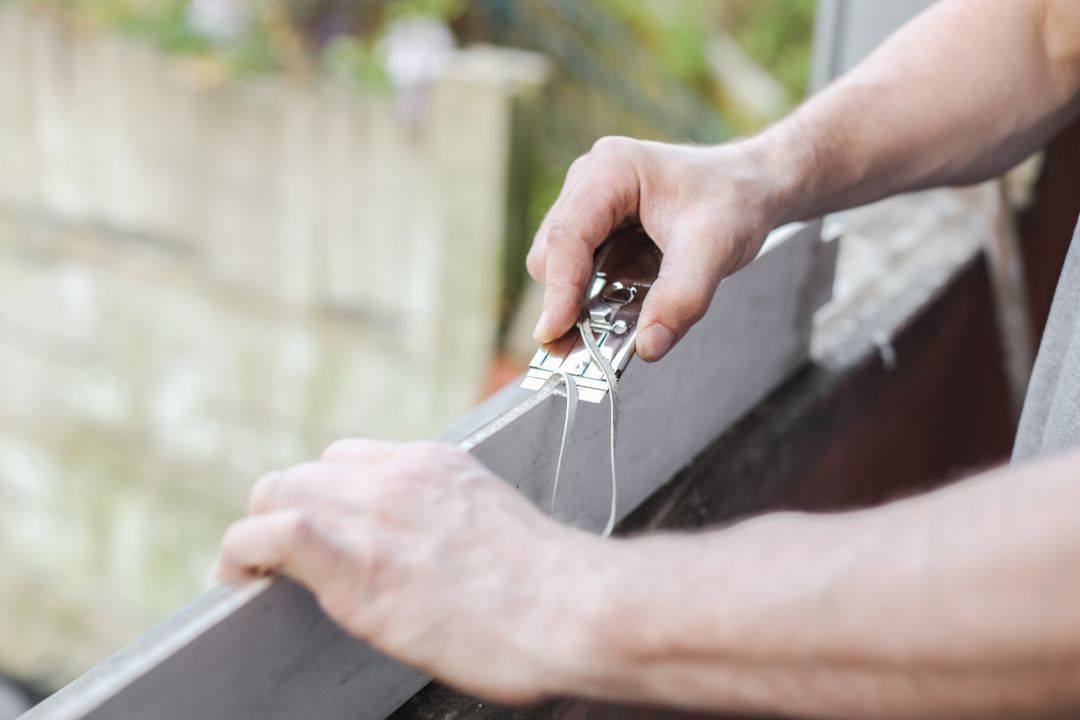 A person removing caulk from a window