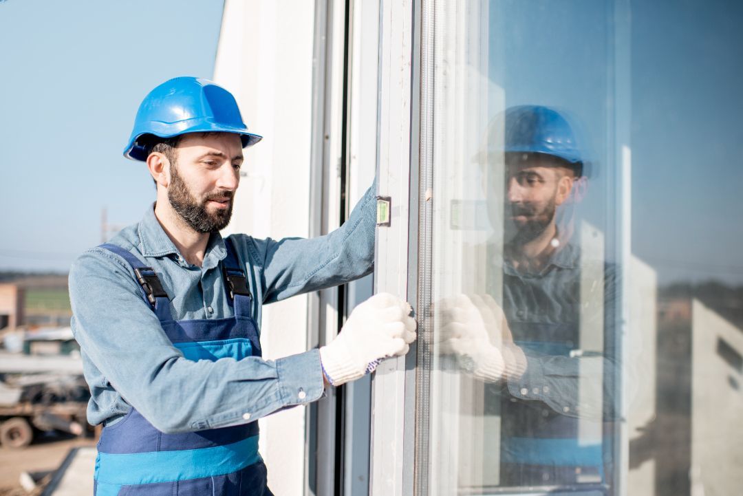 A man wearing a hard hat is inspecting a window.