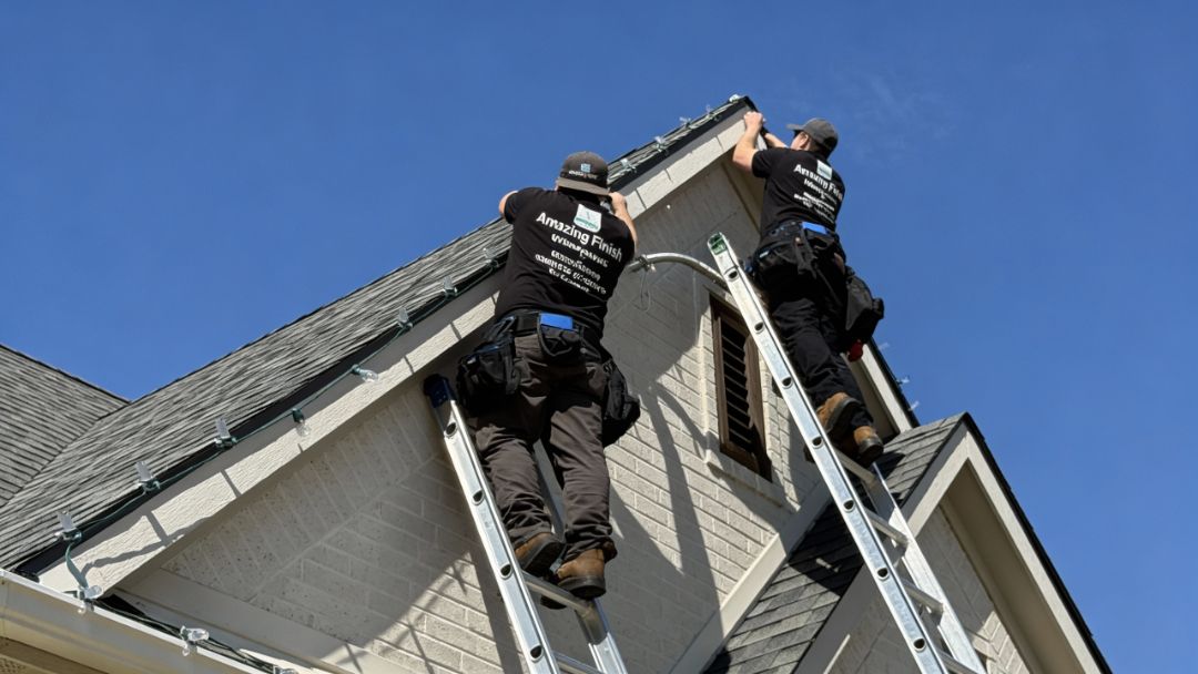 Amazing Finish Windows technicians installing Christmas lights on a steep roof peak to prepare the home for holiday guests.