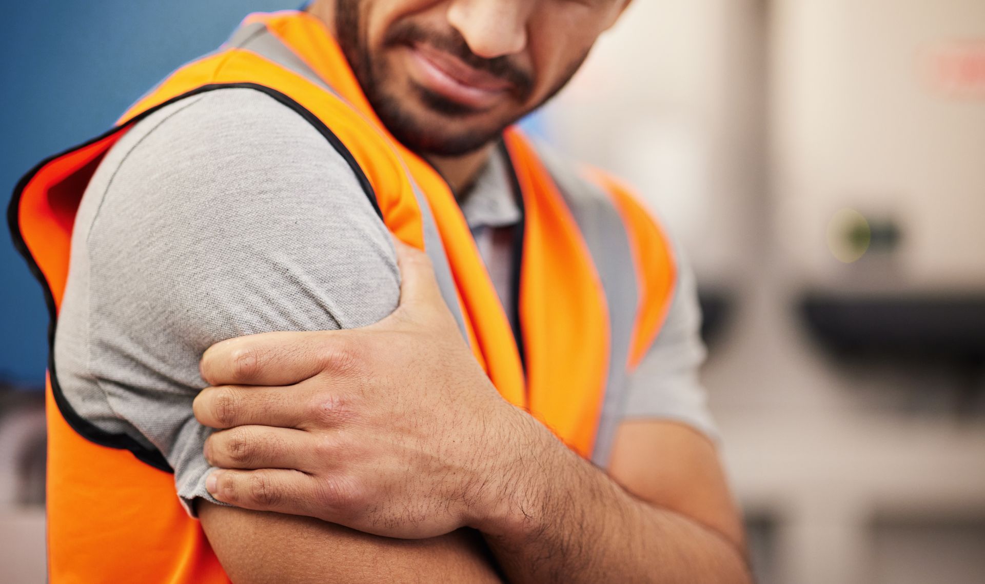a construction worker is holding his shoulder in pain .