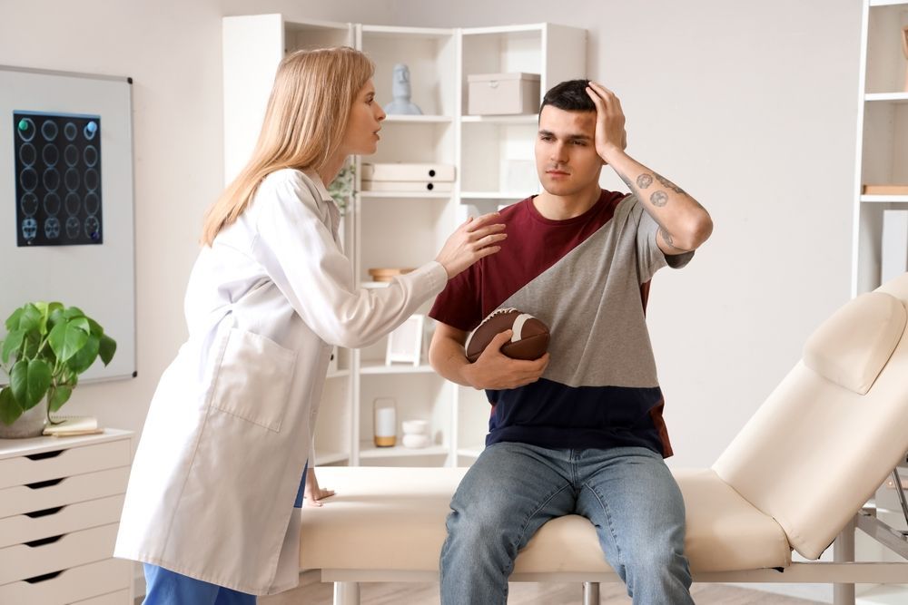 A doctor is talking to a man who is holding a football.