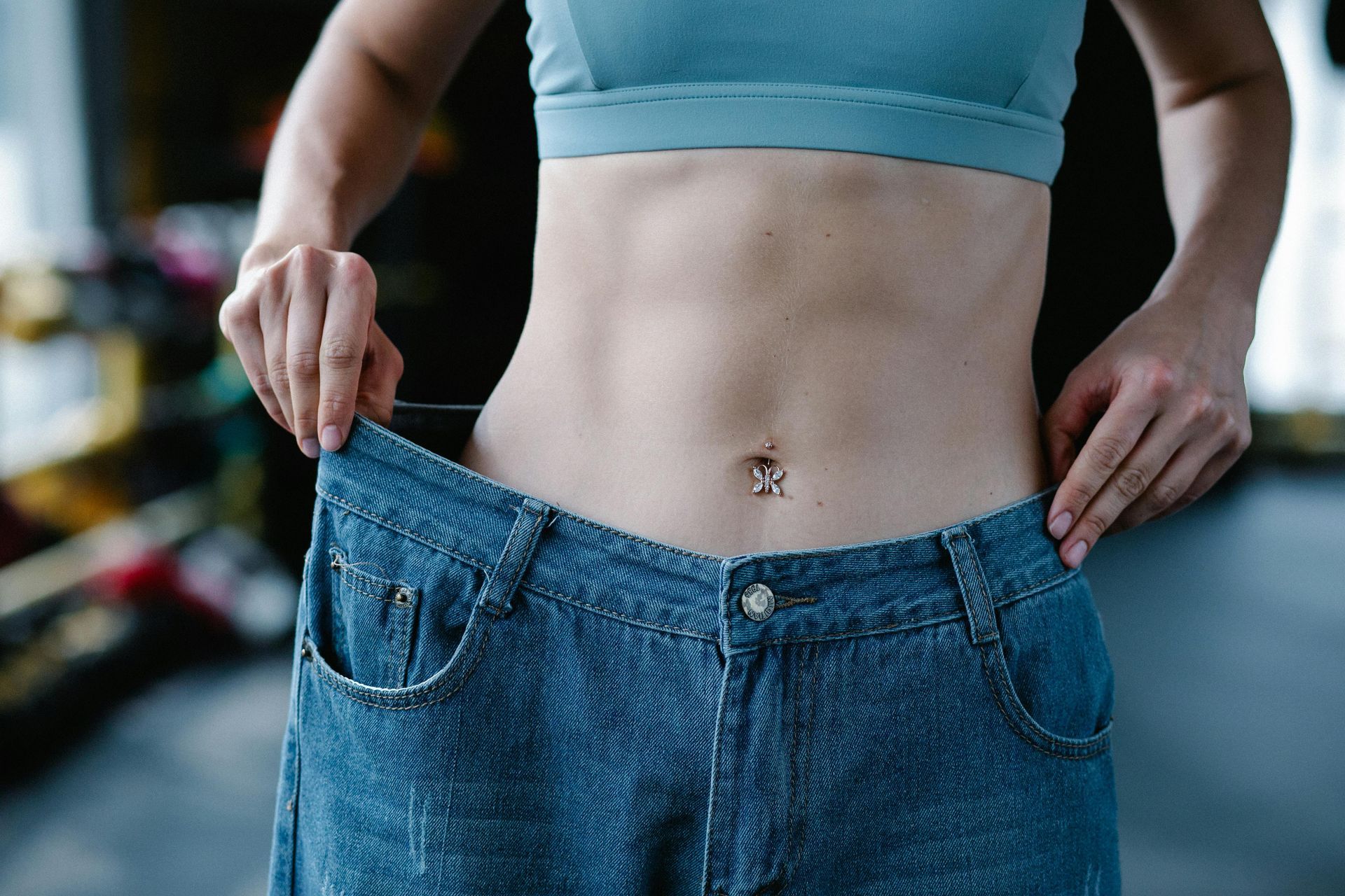 Woman holding up loose jeans, showing weight loss.