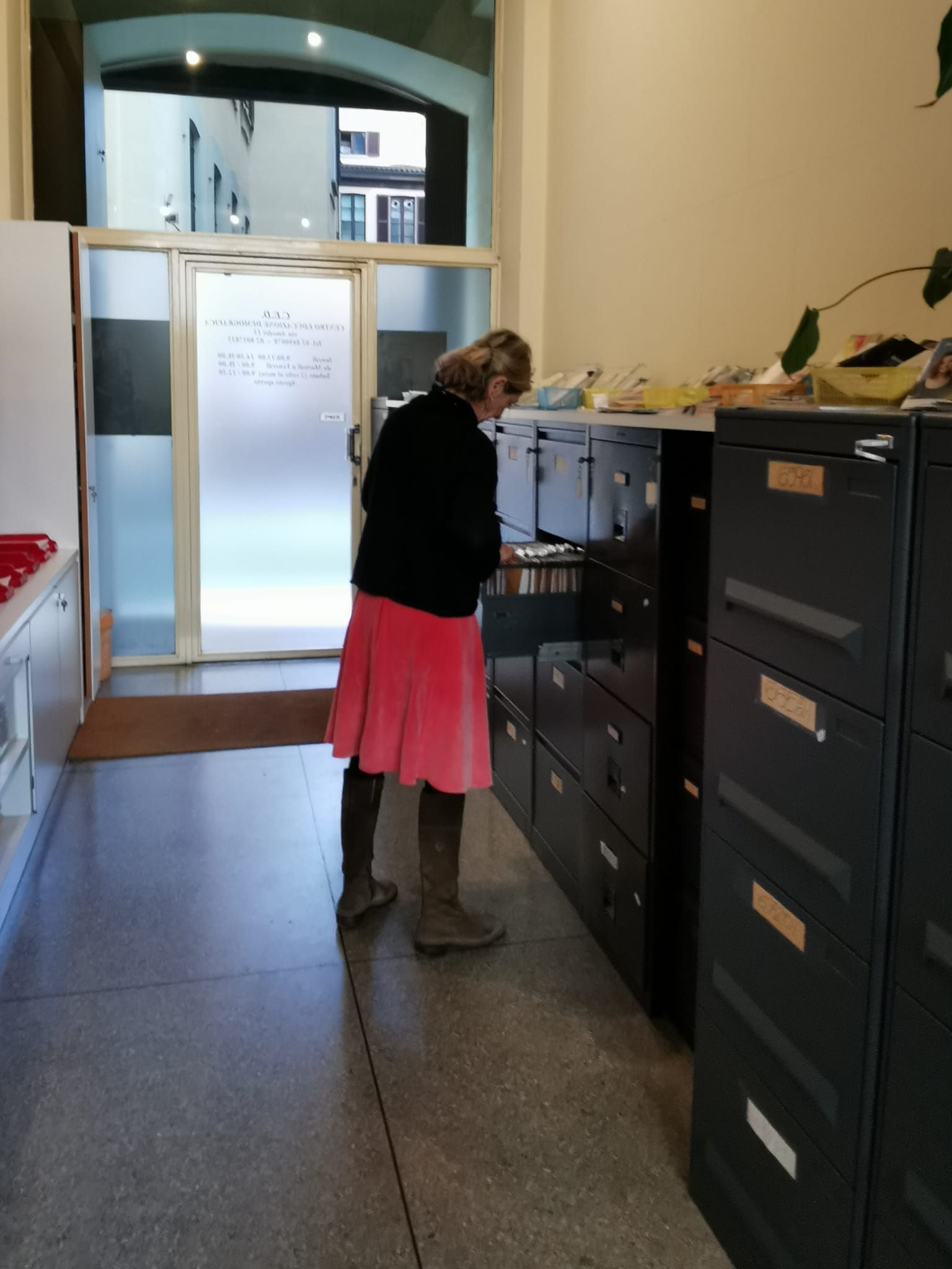 Persona in piedi che osserva gli schedari in un ufficio; sono visibili anche la porta e altri armadi.