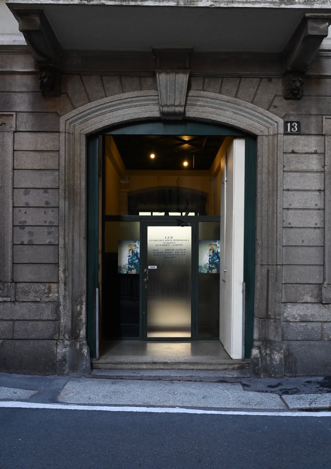 Ingresso di un edificio con un portale ad arco. Una porta bianca parzialmente aperta rivela l'interno.