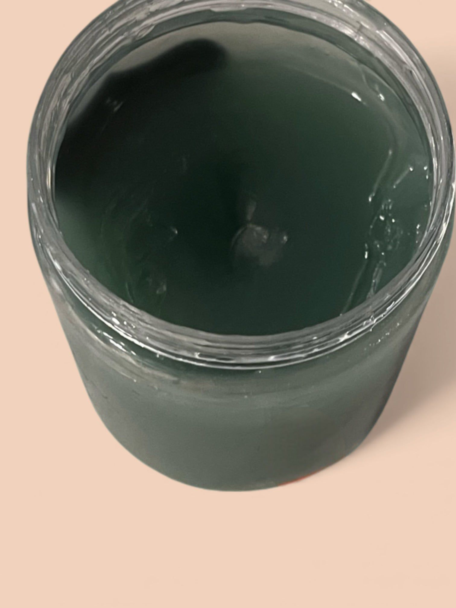 Open jar filled with dark green paint on a light surface