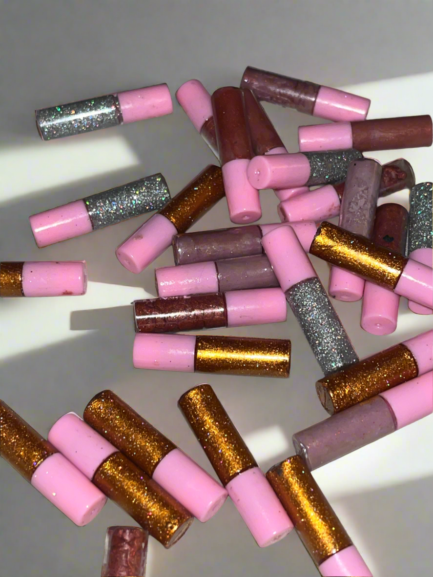 Scattered pink, silver, and gold glitter-tipped party blowers on a white surface