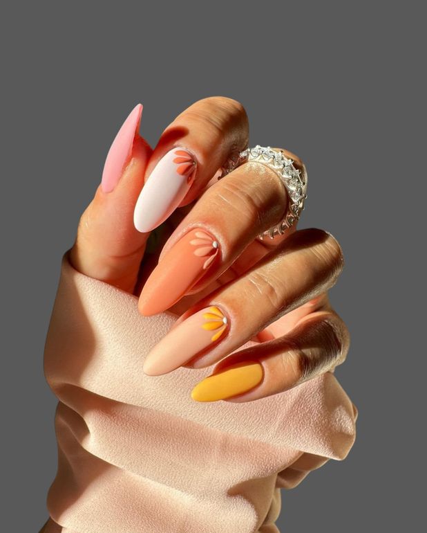 Hand with long pink, white, and orange manicured nails and a jeweled ring