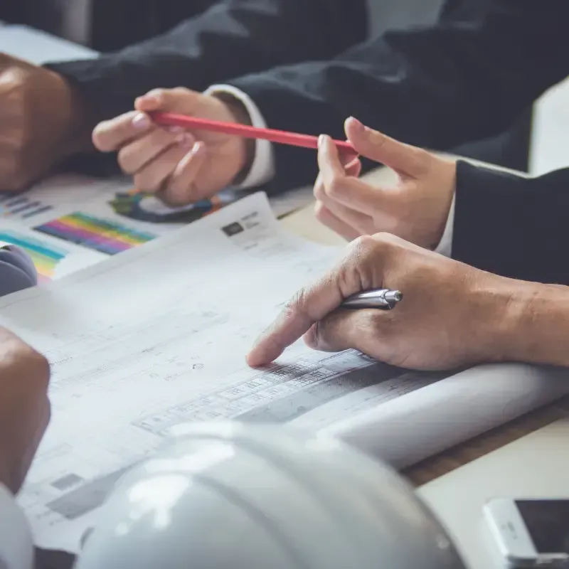 A group of people are sitting at a table looking at a blueprint.