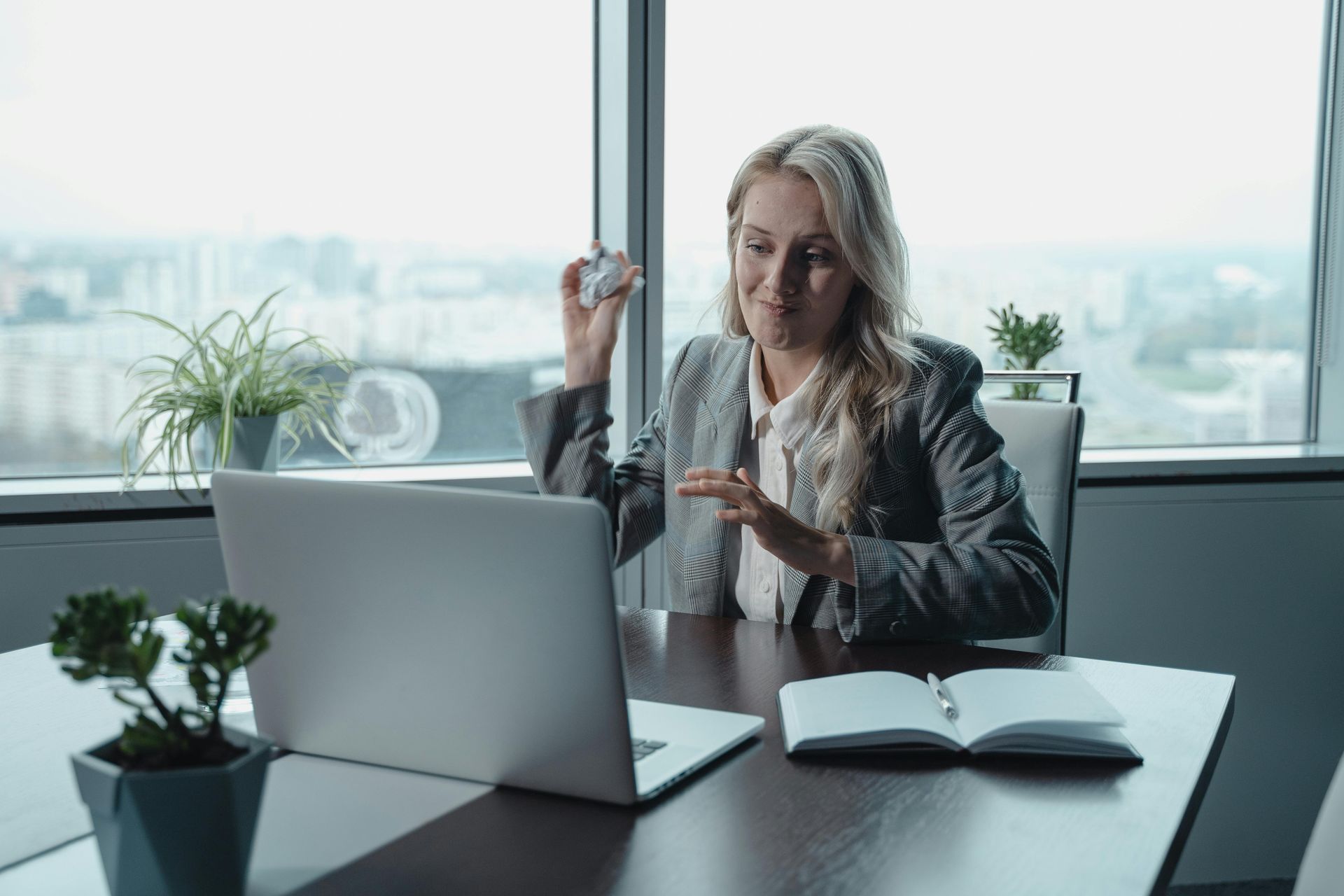 A woman is sitting at a desk in front of a laptop computer.