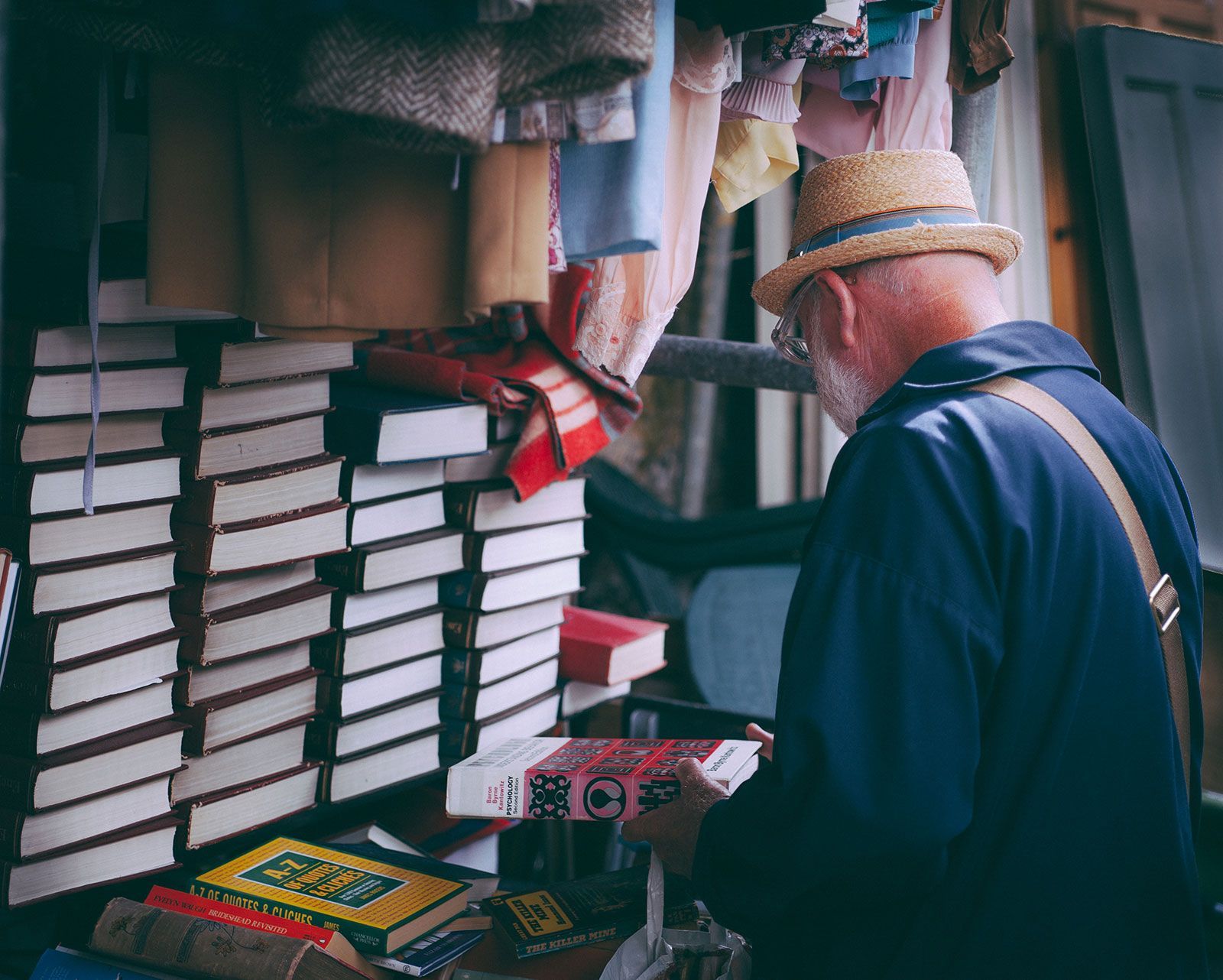 A man wearing a straw hat is reading a book
