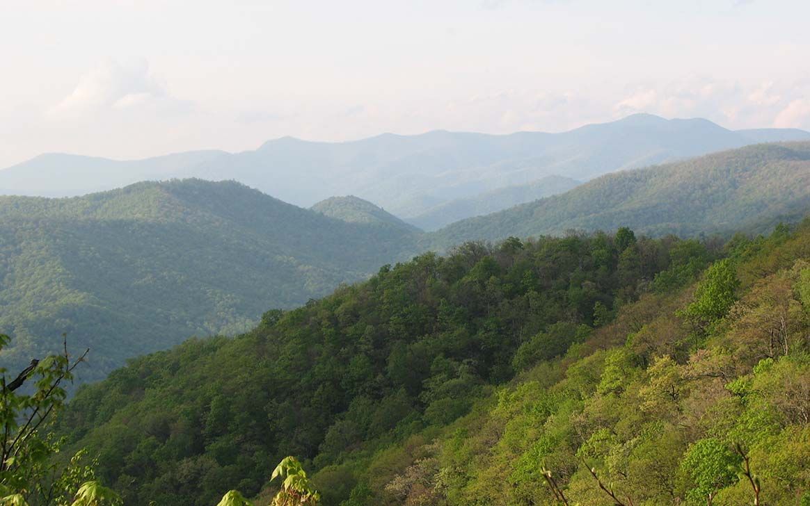 A view of a mountain range with trees and mountains in the background