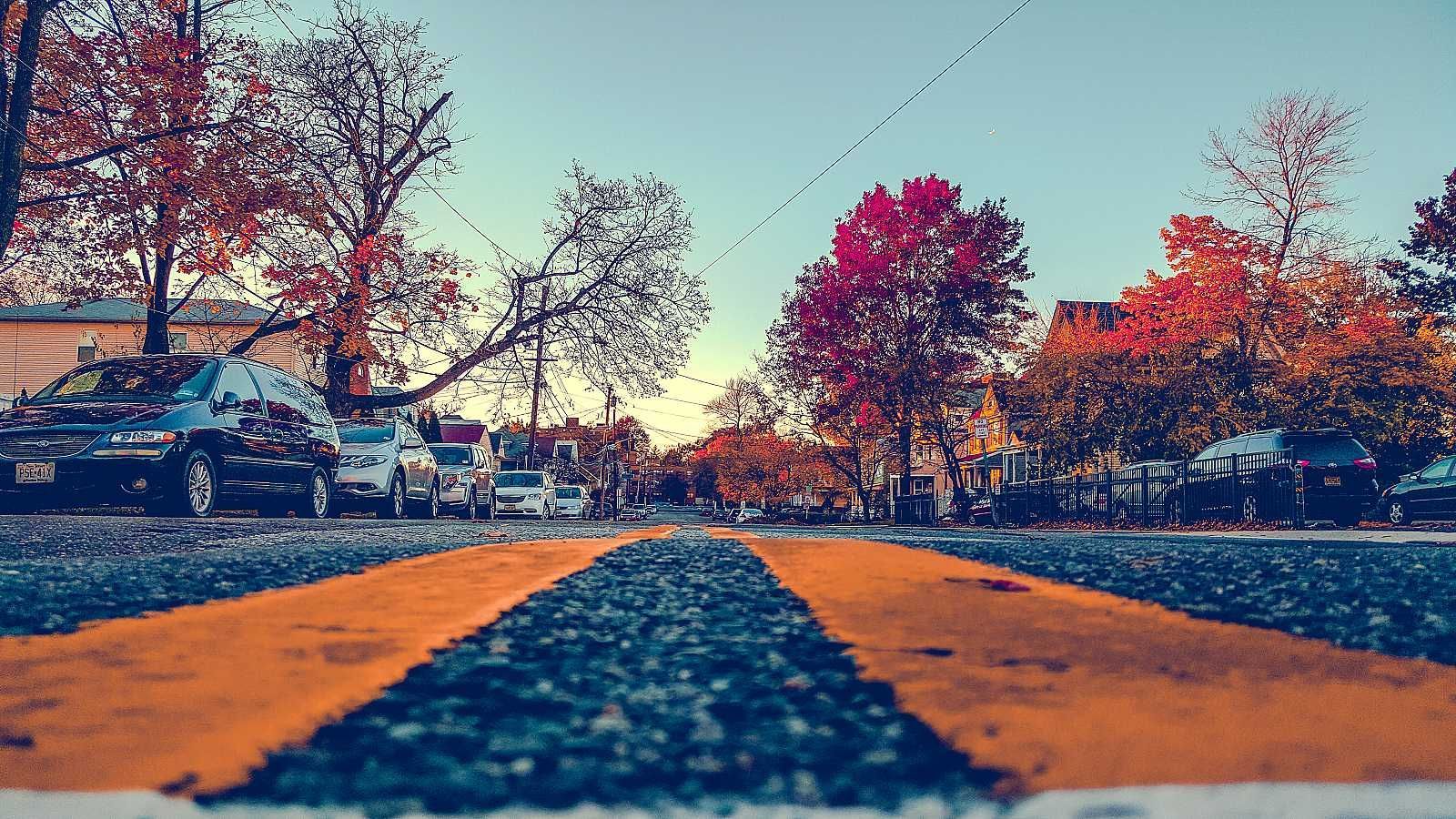 A road with a yellow arrow on it and trees in the background