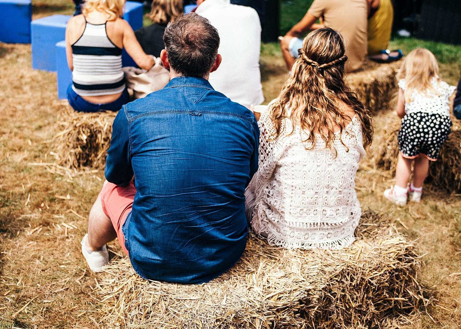 A group of people are sitting on bales of hay.