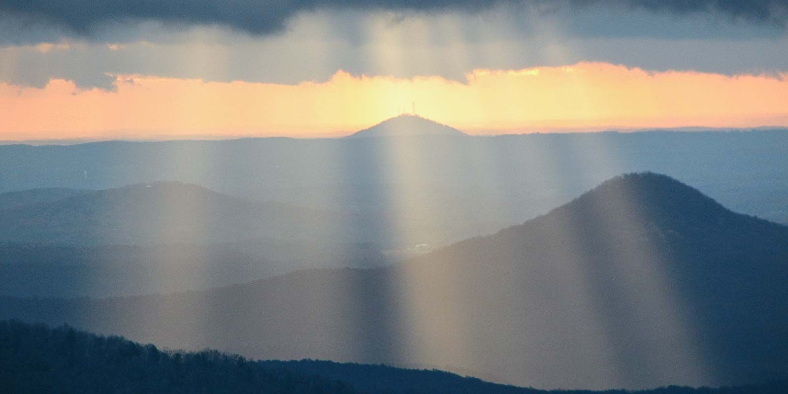The sun is shining through the clouds over the mountains.