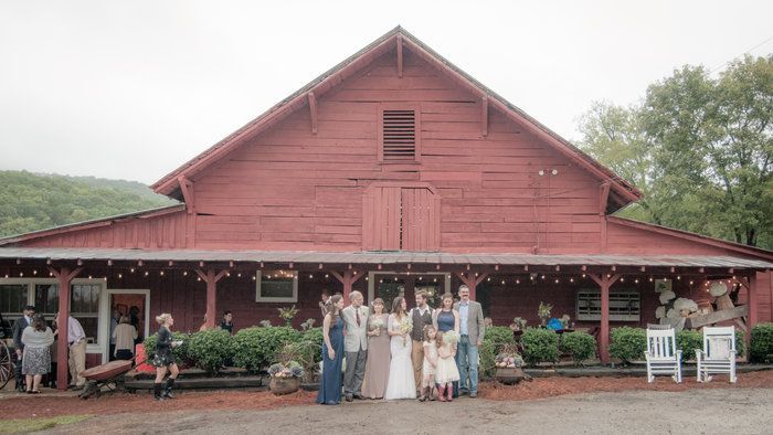 A group of people are posing for a picture in front of a red barn.