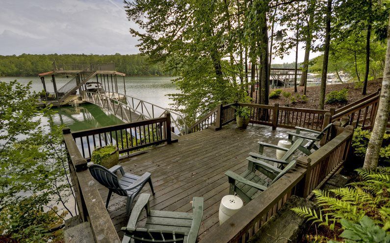 A wooden deck with chairs and a table overlooking a lake
