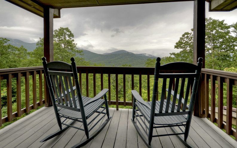 Two rocking chairs on a deck overlooking mountains