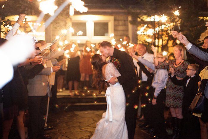 A bride and groom kissing in front of a crowd of people holding sparklers
