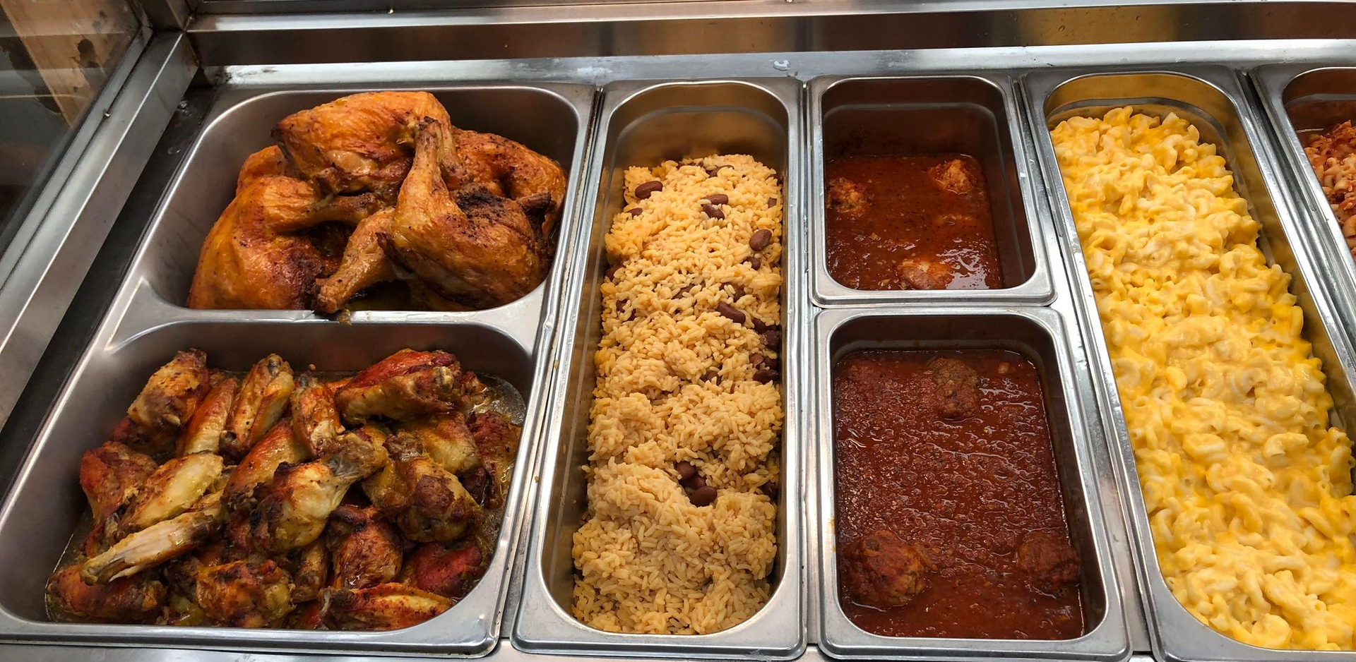 baked chicken legs with rice and beans inside hot display case