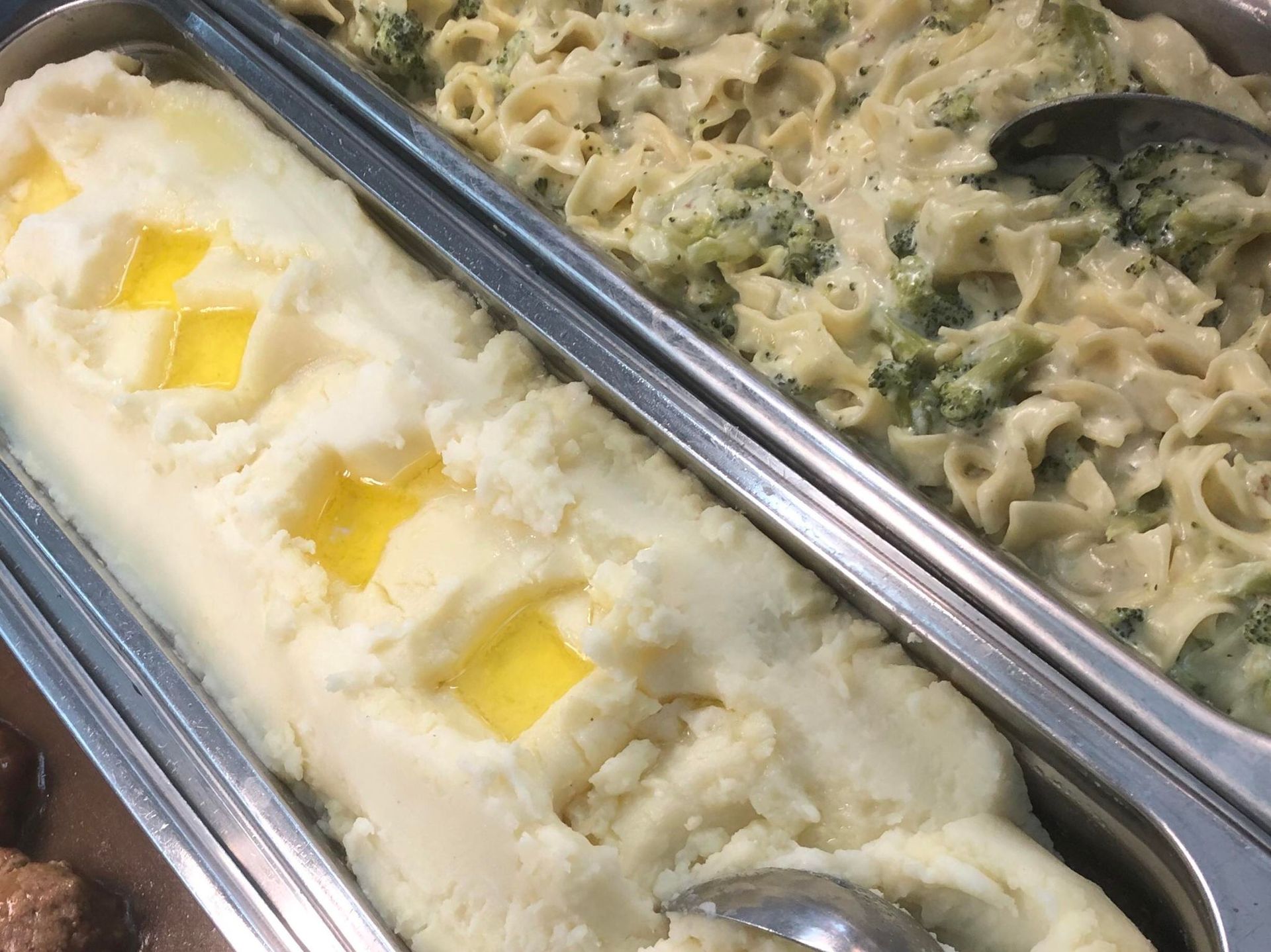 mashed potatoes and broccoli inside hot display case