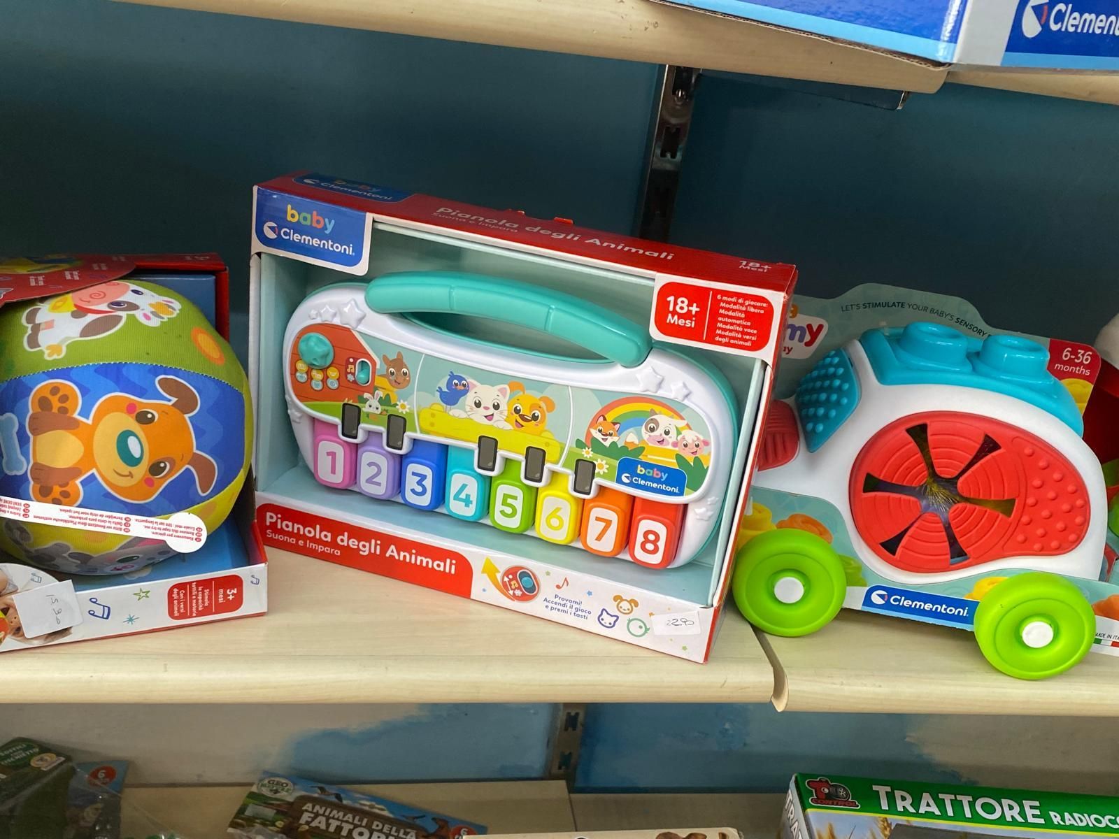 Uno scaffale pieno di giocattoli tra cui un pianoforte e un treno