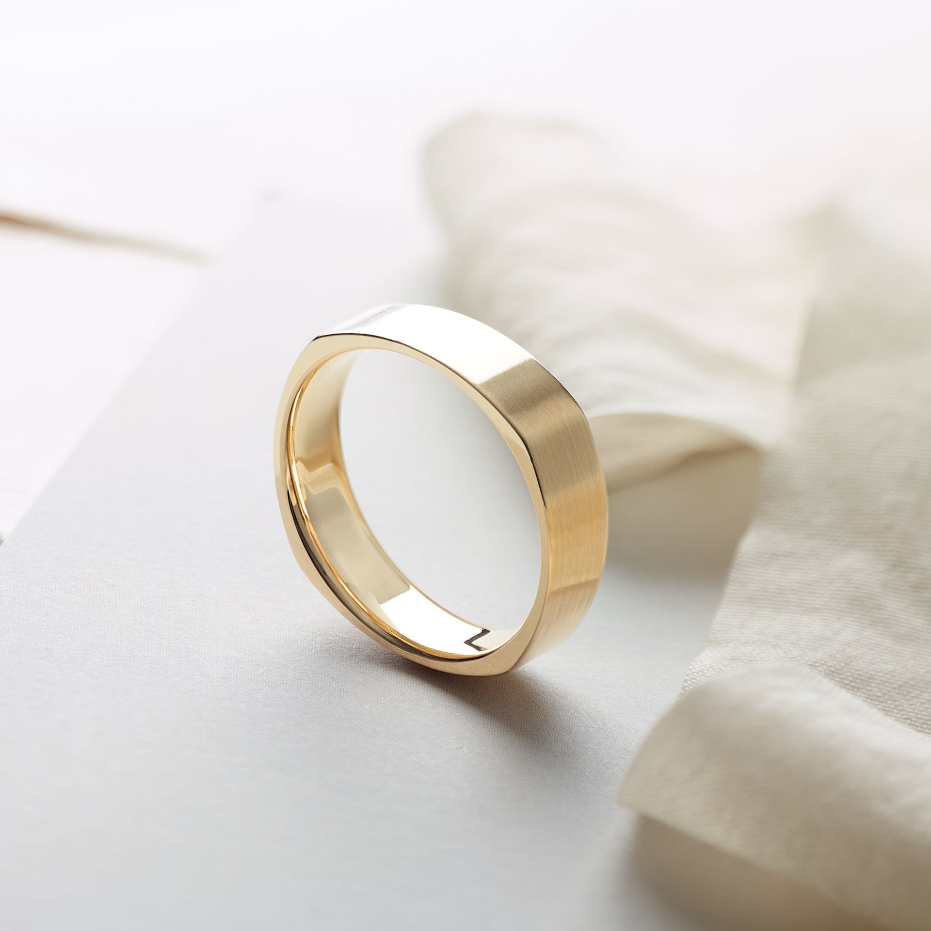 A gold ring is sitting on a white cloth