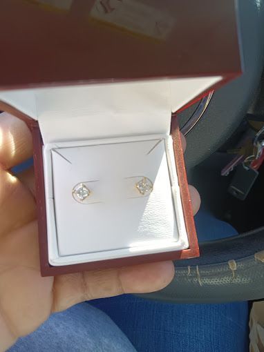 A person is holding a box of earrings in their hand.