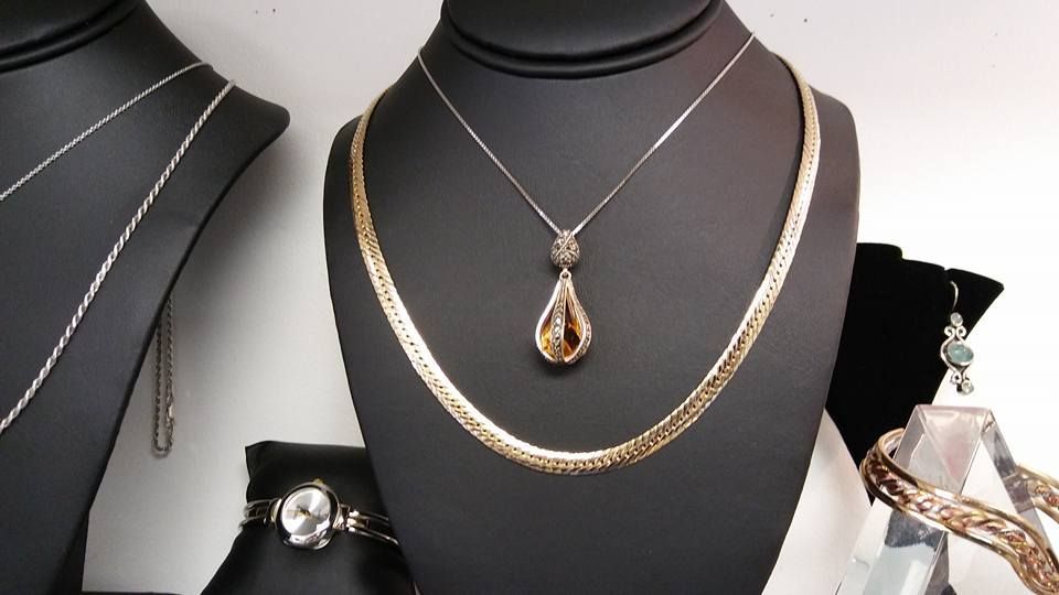 Jewelry display: necklaces of silver and gold on black mannequins.