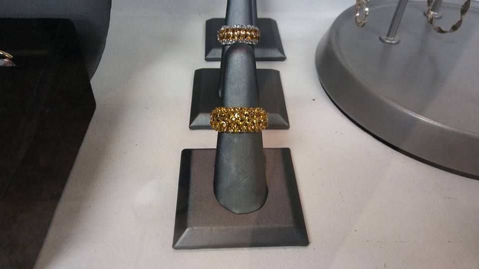 Three rings on a display stand, with the center ring bright gold.