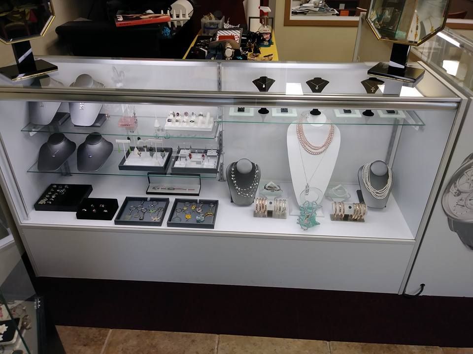 Jewelry display case in a store, showcasing necklaces, rings, and earrings. White and silver tones.