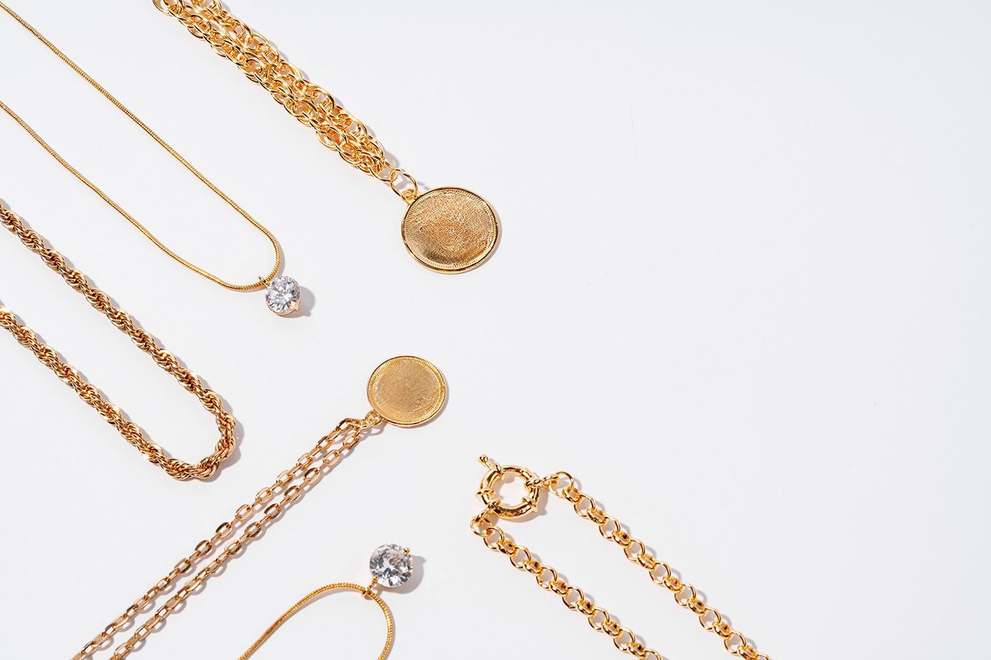 Golden necklaces and a bracelet arranged on a white background.