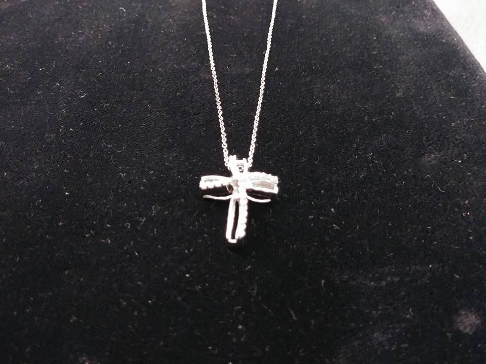 Silver cross pendant necklace on a black velvet background.