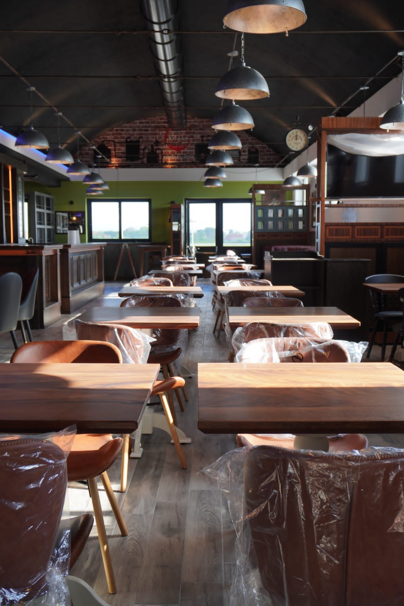 Ristorante vuoto con tavoli e sedie in legno; luci dall'alto.