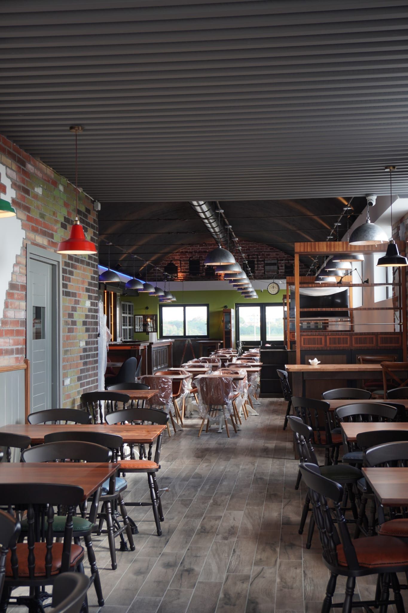 Interno di un pub con tavoli in legno, sedie, pareti in mattoni e soffitto scuro.