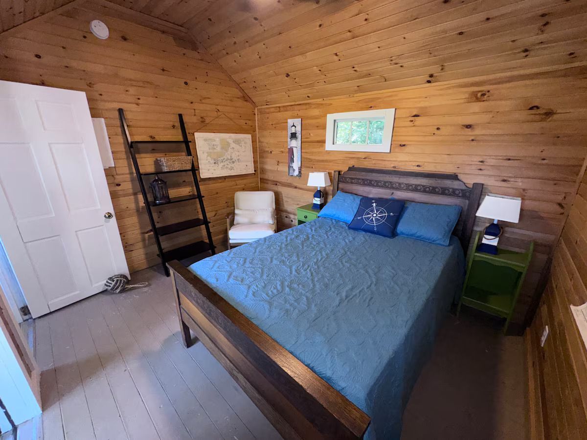 Cozy wood-paneled bedroom with a blue bedspread, nightstands, and a white closet door