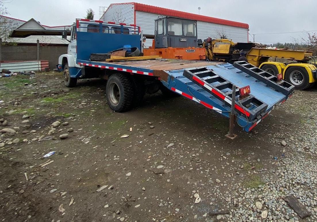 Una grúa azul está estacionada en un estacionamiento de grava