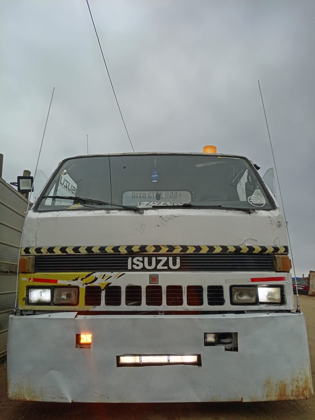 Un camión Isuzu blanco está estacionado al costado de la carretera.