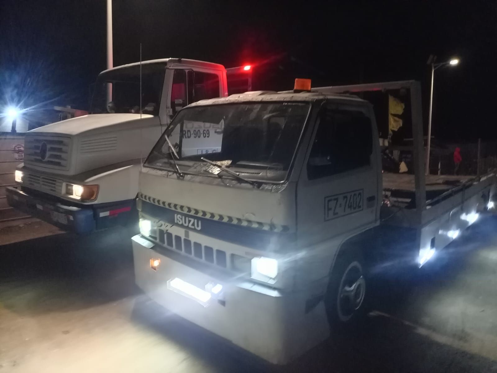 Dos grúas están estacionadas una al lado de la otra por la noche.