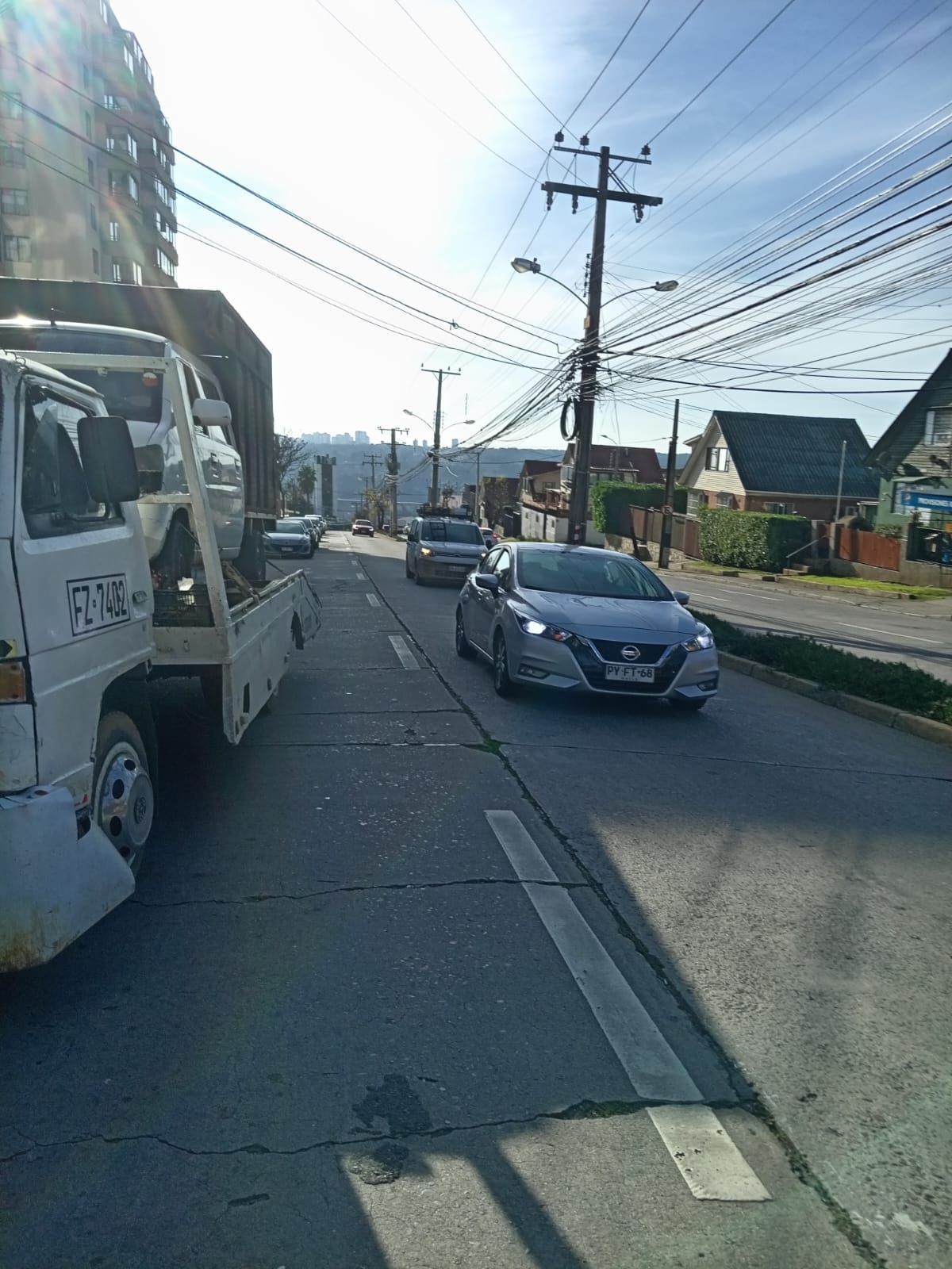 Un coche circula por una calle al lado de una grúa.