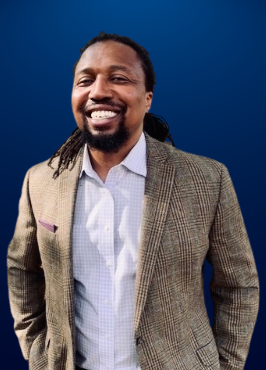 A man with dreadlocks is wearing a suit and smiling.