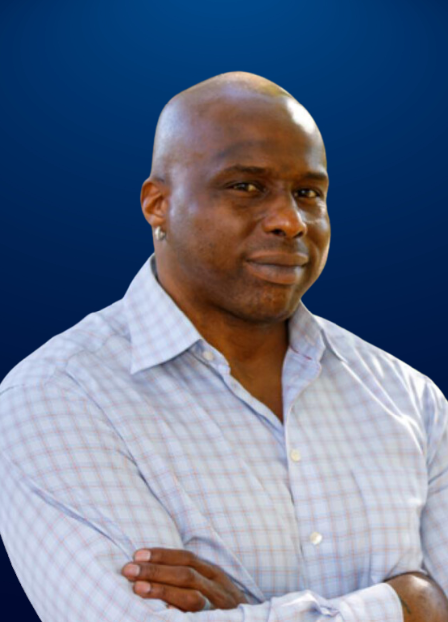 A bald man in a plaid shirt with his arms crossed